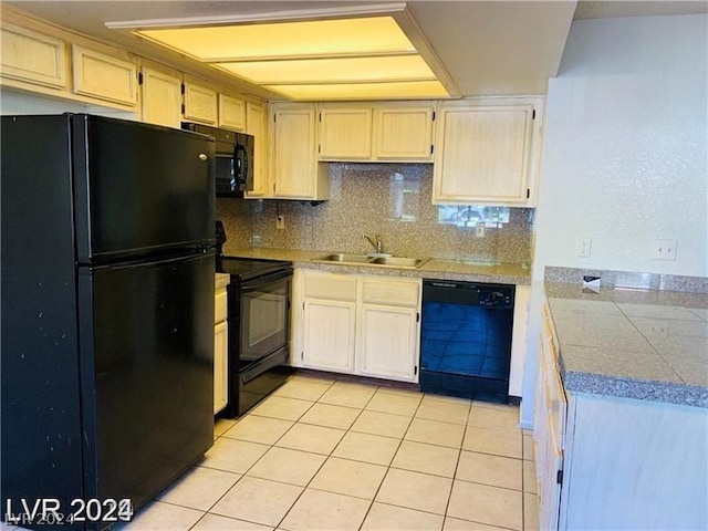 kitchen with light tile patterned floors, sink, tasteful backsplash, and black appliances