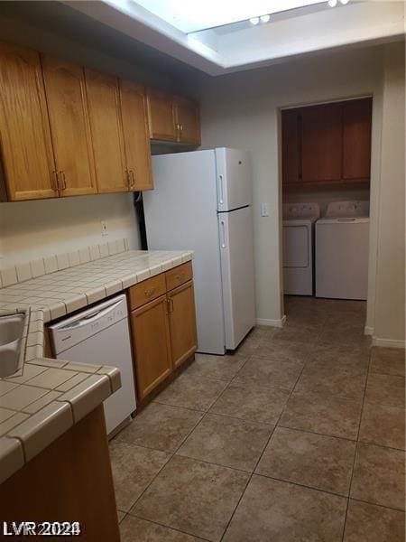 kitchen with tile countertops, washer and dryer, white appliances, and light tile patterned flooring