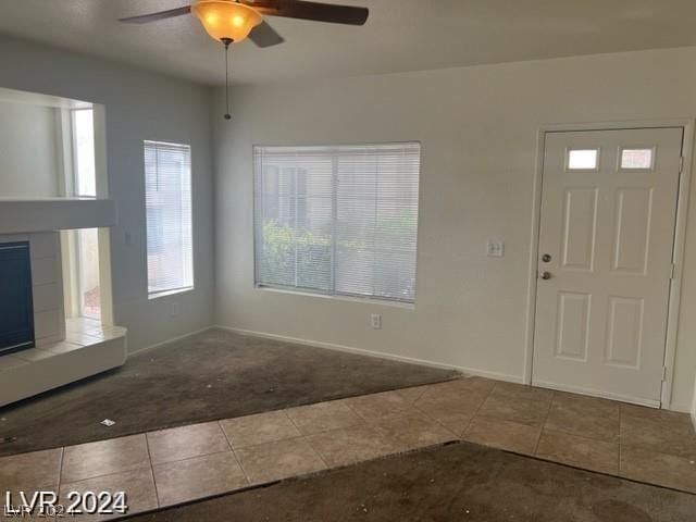 tiled foyer with ceiling fan and a tiled fireplace