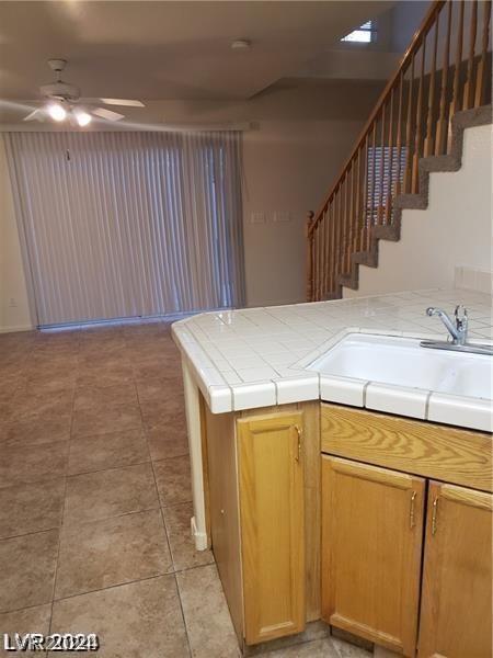 kitchen featuring sink, kitchen peninsula, tile countertops, ceiling fan, and light tile patterned floors