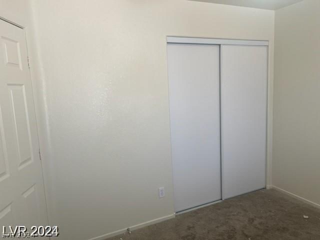 unfurnished bedroom featuring a closet and dark carpet