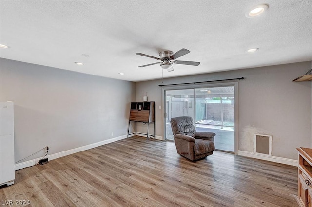 sitting room with ceiling fan, a textured ceiling, and light wood-type flooring