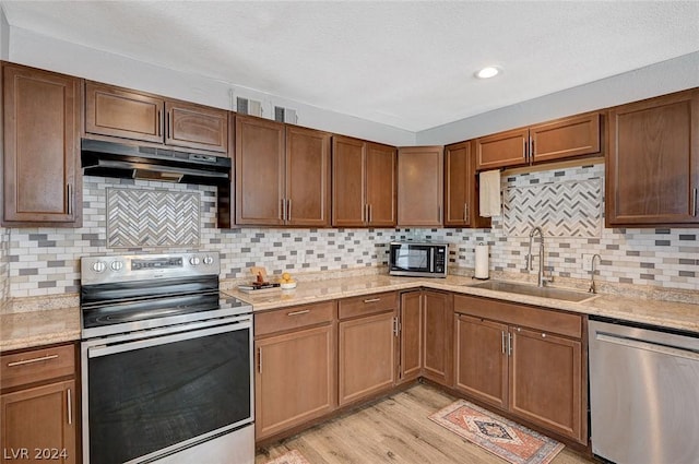 kitchen with decorative backsplash, stainless steel appliances, light hardwood / wood-style floors, and sink