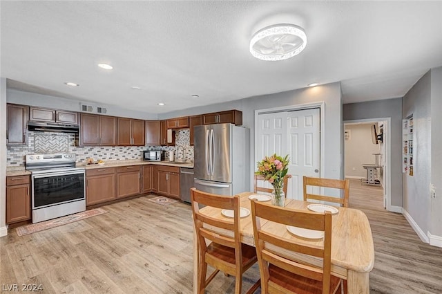 kitchen featuring appliances with stainless steel finishes, tasteful backsplash, and light hardwood / wood-style flooring