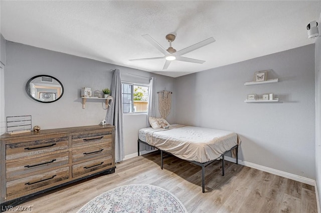 bedroom with a textured ceiling, light wood-type flooring, and ceiling fan