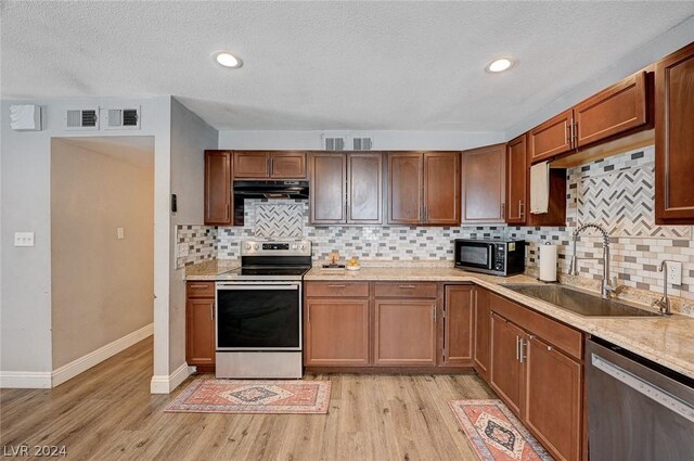 kitchen with decorative backsplash, appliances with stainless steel finishes, light hardwood / wood-style flooring, and sink