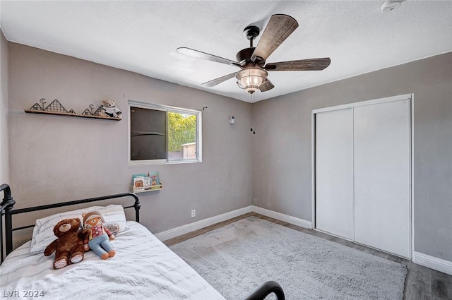 unfurnished bedroom with a textured ceiling, a closet, light hardwood / wood-style flooring, and ceiling fan