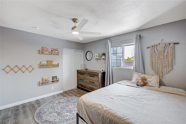 bedroom with hardwood / wood-style floors, a textured ceiling, a closet, and ceiling fan