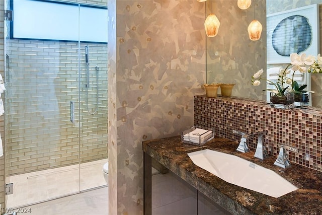 bathroom featuring a wealth of natural light, backsplash, a shower with shower door, and toilet