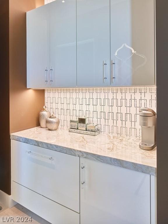 kitchen featuring decorative backsplash, tile patterned floors, and light stone countertops