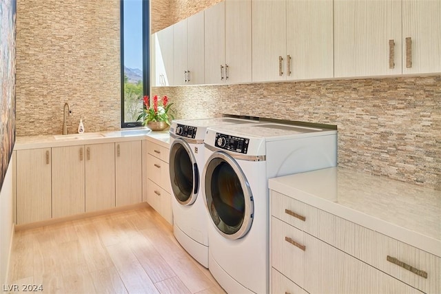 washroom featuring washer and dryer, sink, light wood-type flooring, and cabinets