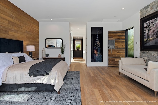 bedroom with hardwood / wood-style floors and wooden walls