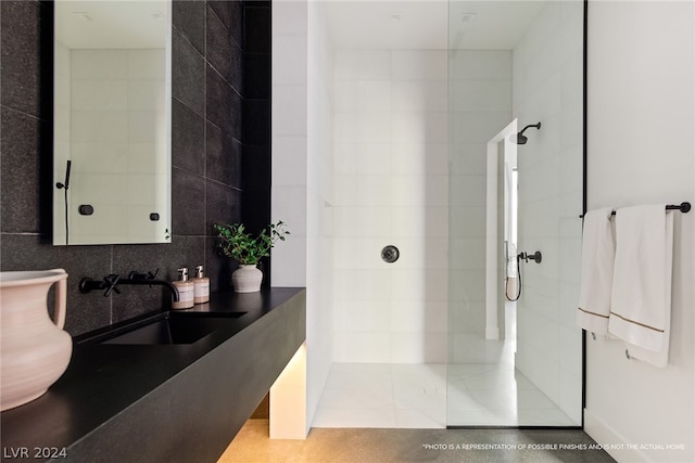 bathroom with sink, a tile shower, and tile walls