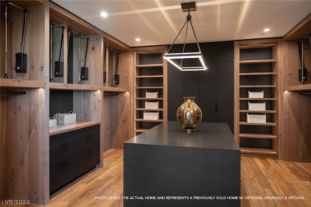 walk in closet with light hardwood / wood-style flooring