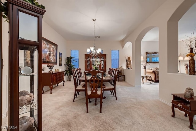 dining space with arched walkways, light colored carpet, baseboards, and an inviting chandelier