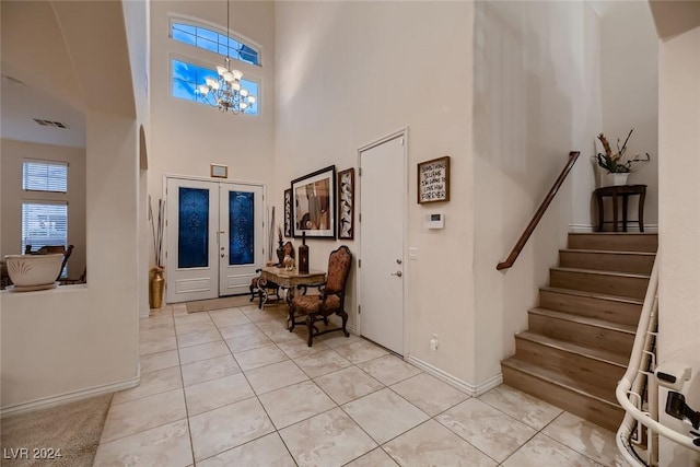 entryway with light tile patterned flooring, stairway, a chandelier, and french doors