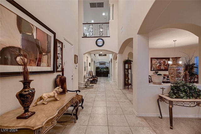 hallway featuring visible vents, arched walkways, a notable chandelier, and tile patterned floors