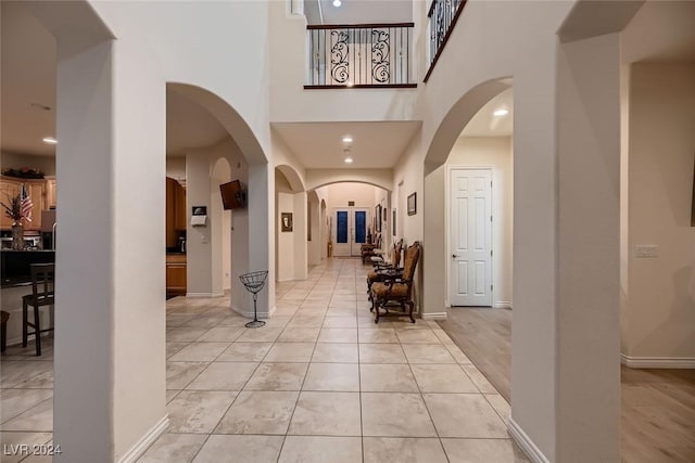 foyer entrance with a towering ceiling, light tile patterned floors, arched walkways, and recessed lighting