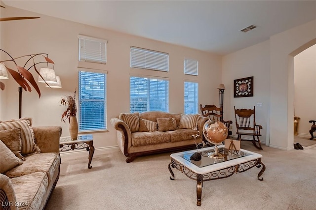 carpeted living area featuring arched walkways, visible vents, and baseboards