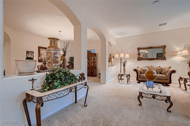 carpeted living area featuring arched walkways, visible vents, and baseboards