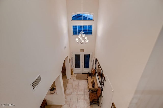 entryway with light tile patterned floors, visible vents, an inviting chandelier, a high ceiling, and french doors