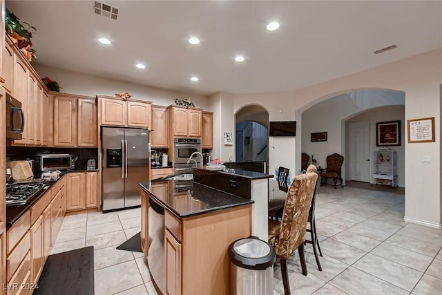 kitchen featuring appliances with stainless steel finishes, arched walkways, visible vents, and a kitchen bar