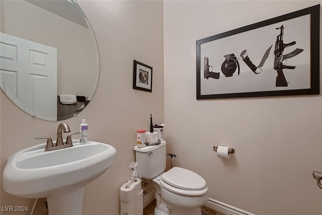 half bathroom with baseboards, a sink, and toilet