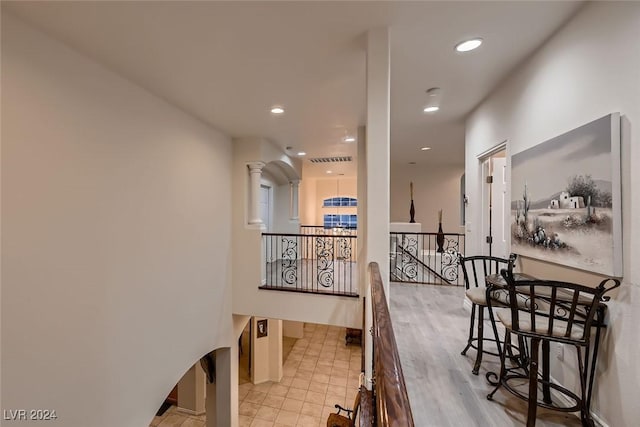 corridor with visible vents, ornate columns, an upstairs landing, and recessed lighting