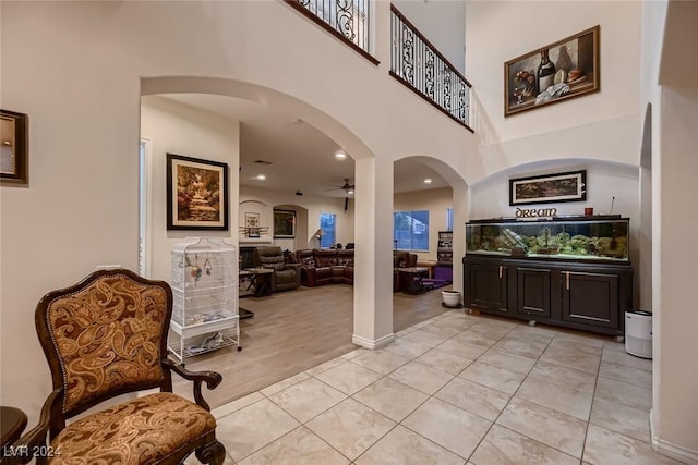 foyer featuring light tile patterned floors, arched walkways, ceiling fan, a high ceiling, and recessed lighting