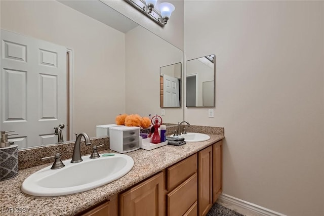 bathroom featuring double vanity, baseboards, and a sink