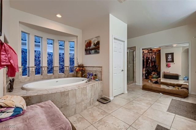 bathroom with a shower stall, a bath, and tile patterned floors