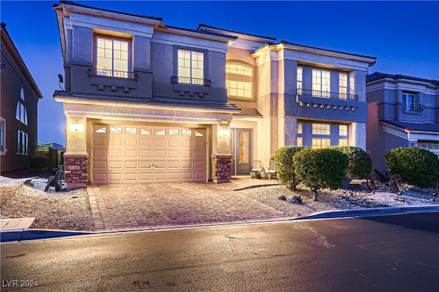 view of front of home featuring decorative driveway, an attached garage, and stucco siding