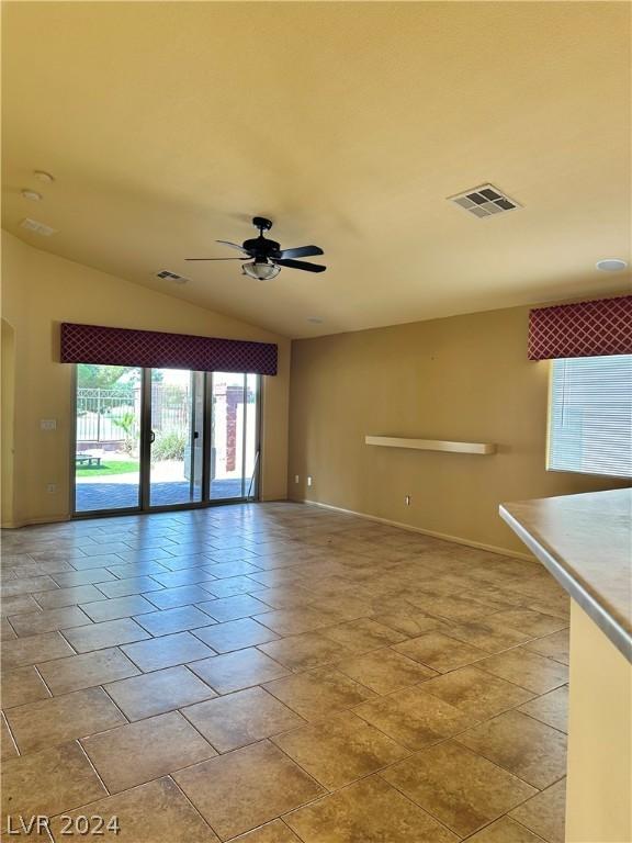 empty room featuring ceiling fan, vaulted ceiling, and light tile patterned floors