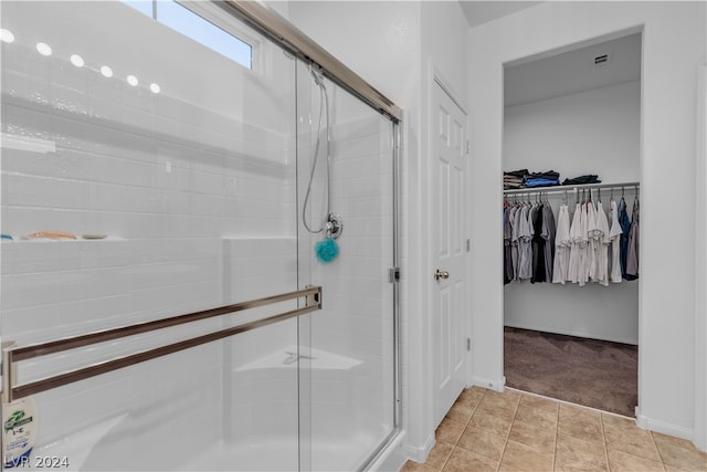 bathroom featuring a stall shower, tile patterned flooring, a spacious closet, and baseboards