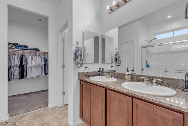 bathroom featuring a stall shower, a walk in closet, a sink, and tile patterned floors