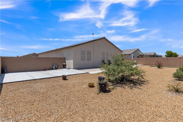 rear view of property featuring a patio, a fenced backyard, and stucco siding