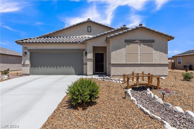 view of front of property featuring a garage, a tiled roof, concrete driveway, and stucco siding