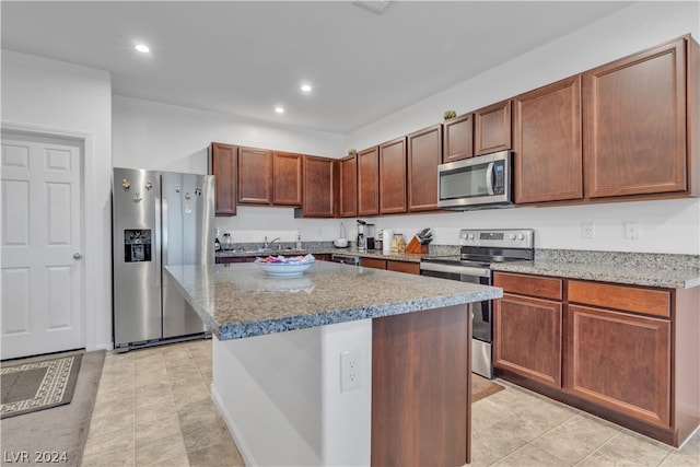 kitchen featuring appliances with stainless steel finishes, a center island, light stone counters, and recessed lighting