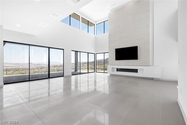 unfurnished living room with a high ceiling, light tile patterned floors, and a wealth of natural light