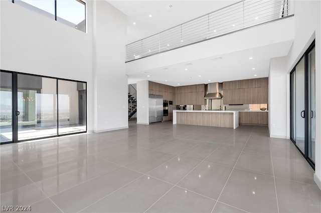 unfurnished living room featuring a wealth of natural light, a high ceiling, and tile patterned flooring