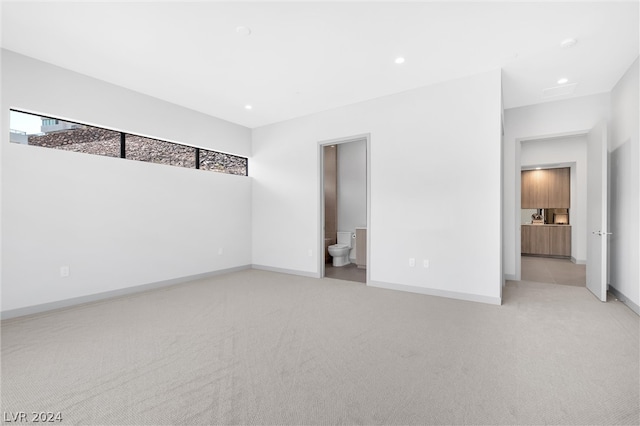 unfurnished bedroom featuring ensuite bathroom and light carpet