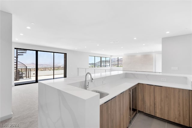 kitchen with light carpet, kitchen peninsula, sink, and light stone countertops