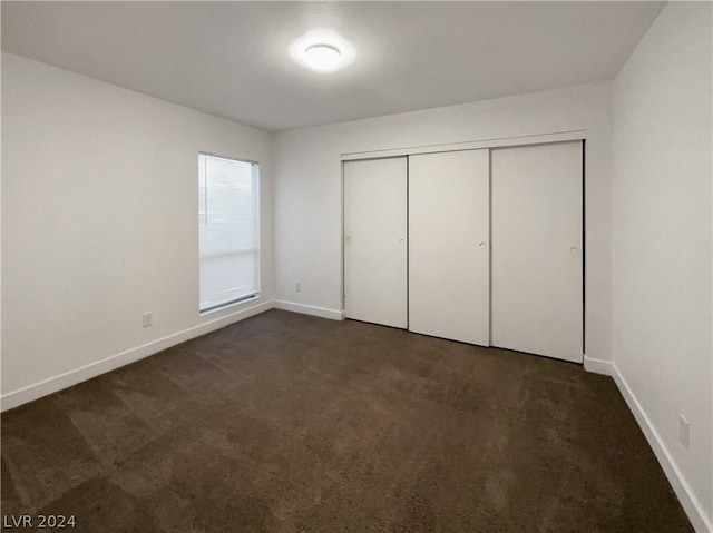 unfurnished bedroom featuring a closet and dark colored carpet