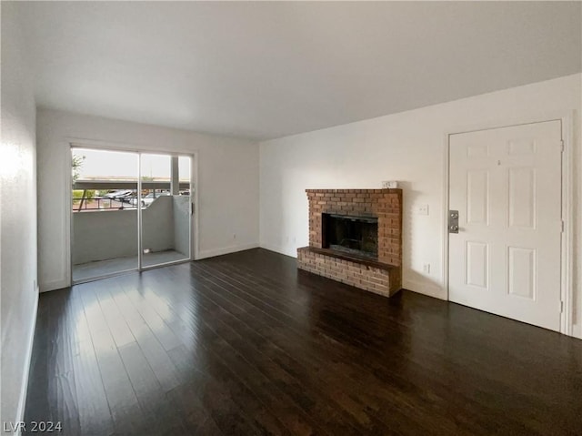 unfurnished living room with a brick fireplace and dark hardwood / wood-style floors