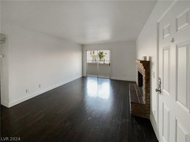 unfurnished living room with a brick fireplace and dark wood-type flooring