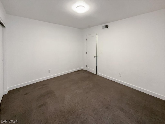 unfurnished room featuring dark carpet