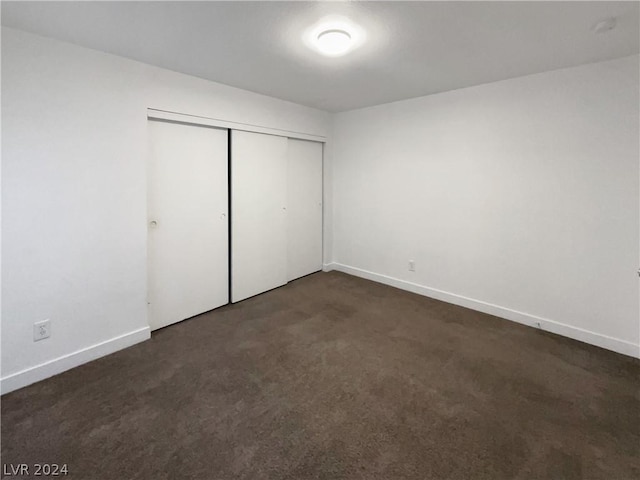 unfurnished bedroom with a closet and dark colored carpet