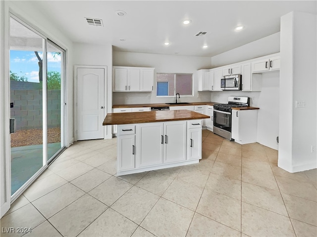 kitchen featuring wooden counters, a kitchen island, stainless steel appliances, sink, and white cabinetry