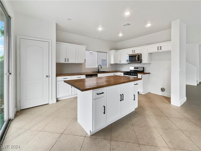 kitchen featuring wooden counters, a center island, stainless steel appliances, and white cabinetry