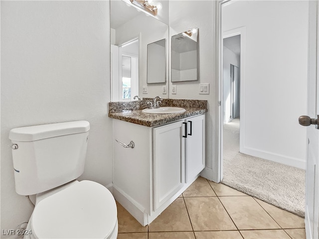 bathroom with toilet, vanity, and tile patterned floors